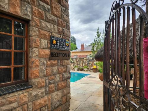 a sign on the side of a stone house with a pool at Foundation Stones Lodge Mafikeng in Mahikeng