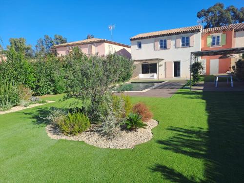 une cour avec de l'herbe verte et une maison dans l'établissement Gridelaide26 - Les jardins d'Adelaïde - Grimaud - Golfe de Saint-Tropez - Villa avec piscine privée proche de la mer, à Grimaud