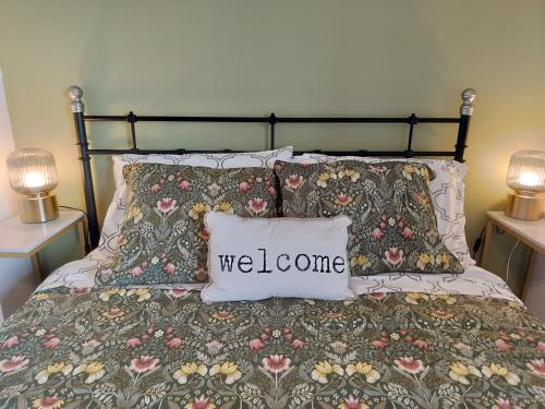 a bed with a bedspread with a welcome pillow on it at Xixi Cama Bed & Breakfast in Bombardeira
