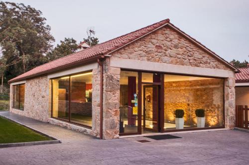 a building with large glass doors in a yard at Hotel Alén do Mar in Finisterre