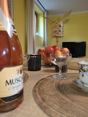 a bottle of wine on a table with a bowl of apples at Apartament Biała Flaga nad Jeziorem Charzykowskim in Charzykowy