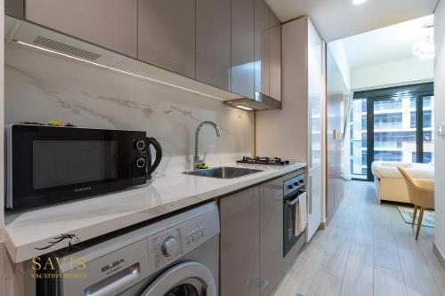 a kitchen with a sink and a microwave at A Modern Haven Cozy Studio in Azizi Riviera Meydan in Dubai