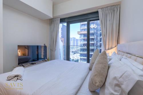 Un dormitorio con una gran cama blanca con una gran ventana. en Savis Homes - Azizi Riviera 43 - Chic Studio Near Downtown and Business Bay, en Dubái