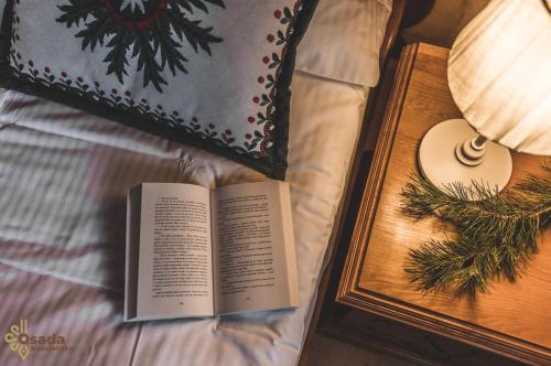 a book sitting on a bed next to a side table at Osada Kościelisko - Tatry na Wyciągnięcie Ręki in Kościelisko