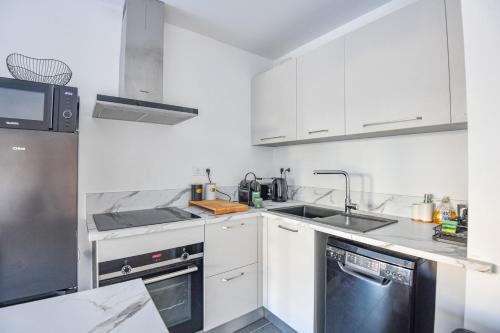 une cuisine blanche avec un évier et un lave-vaisselle dans l'établissement Le Vallon - Bel appart 2 ch avec terrasse, à Marseille