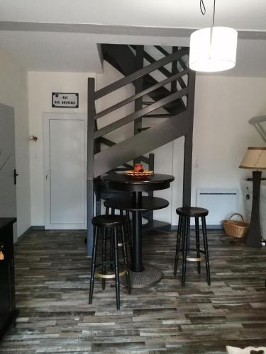 une chambre avec une table, des tabourets et un escalier dans l'établissement La Chèvrerie de Saint-Vigor, à Saint-Vigor-dʼYmonville