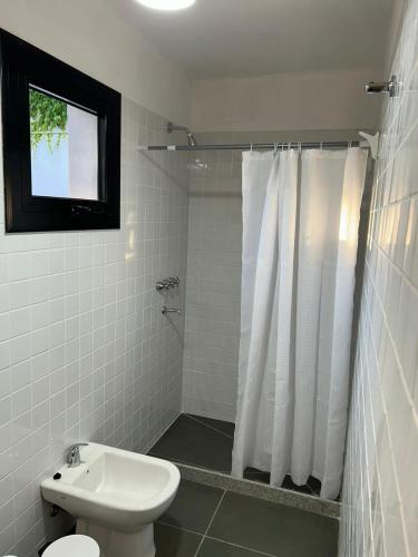 a white bathroom with a toilet and a shower at Casa de la Flor by Posada de la Flor in Colonia del Sacramento