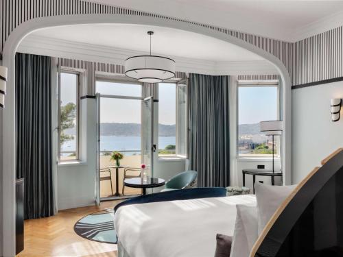 a hotel room with a bed and large windows at The 1932 Hotel & Spa Cap d'Antibes - MGallery Collection in Juan-les-Pins