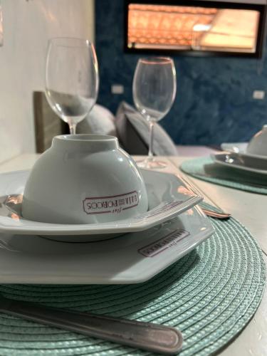 a table with a plate and two wine glasses on it at Flats Baia dos Porcos in Fernando de Noronha