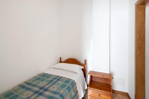 a small bedroom with a bed and a wooden nightstand at Residence Malibu Appartamento 4 in Falcade