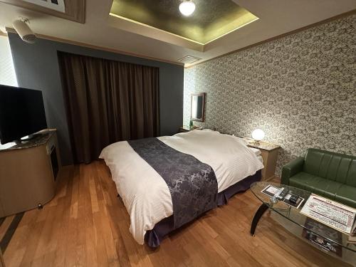 a bedroom with a bed and a couch and a table at ホテルk2 in Itoshima
