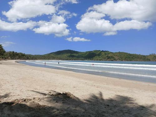 a beach with people swimming in the water at Kubo Inn & Beach Camp in El Nido