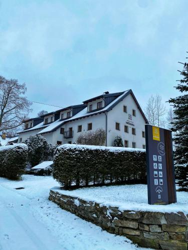 a sign in the snow in front of a house at Horský Hotel Sněženka in Hynčice pod Sušinou