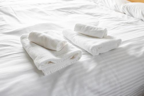 two towels sitting on top of a white bed at Stellar Nishi-Kojiya in Tokyo