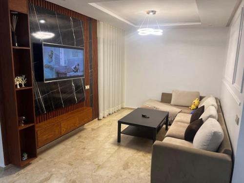 a living room with a couch and a tv at Appartement de luxe à Casablanca in Aïn Sebaa