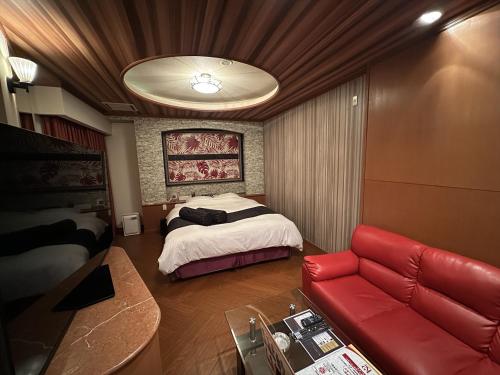 a bedroom with a bed and a red couch at ホテルk2 in Itoshima