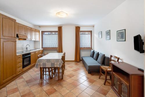 a kitchen and living room with a table and a couch at Residence Malibu Appartamento 8 in Falcade