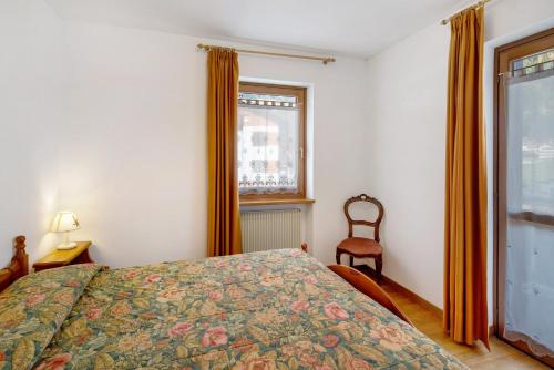 a bedroom with a bed and a window and a chair at Residence Malibu Appartamento 5 in Falcade