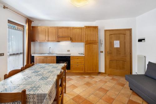 a kitchen with wooden cabinets and a table and a couch at Residence Malibu Appartamento 5 in Falcade