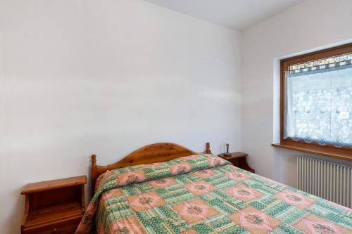 a bedroom with a bed with a comforter and a window at Residence Malibu Appartamento 2 in Falcade