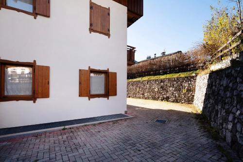 a building with two windows and a stone wall at Residence Malibu Appartamento 2 in Falcade