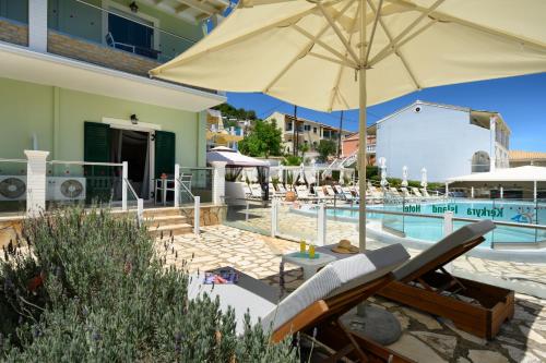 a patio with an umbrella next to a swimming pool at Kerkyra Island Hotel in Mesongi