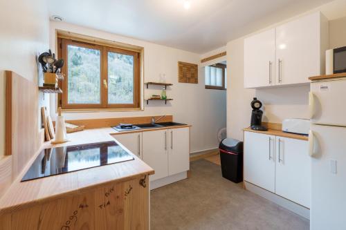 une cuisine avec des armoires blanches, un évier et une fenêtre dans l'établissement Les Jonquilles - 3 chambres et garage privé, à Cornimont