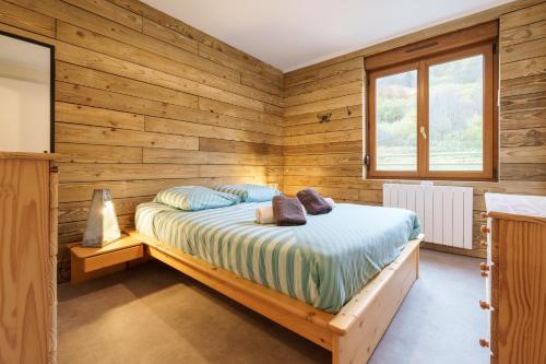 - une chambre avec des murs en bois et un lit avec des oreillers dans l'établissement Les Jonquilles - 3 chambres et garage privé, à Cornimont