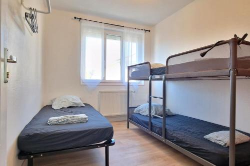 two bunk beds in a room with a window at Maison à Aurillac - 3 chambres - Arrivée autonome in Aurillac