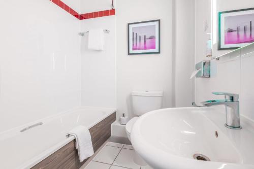 a white bathroom with a tub and a sink at Leonardo Hotel Brighton in Brighton & Hove