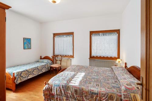a bedroom with two beds and two windows at Residence Malibu Appartamento 3 in Falcade
