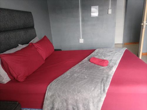 a bed with red pillows and a red pillow on it at Monarca inn - Affordable Accomodation in makwane molapo location Qwaqwa in Phuthaditjhaba