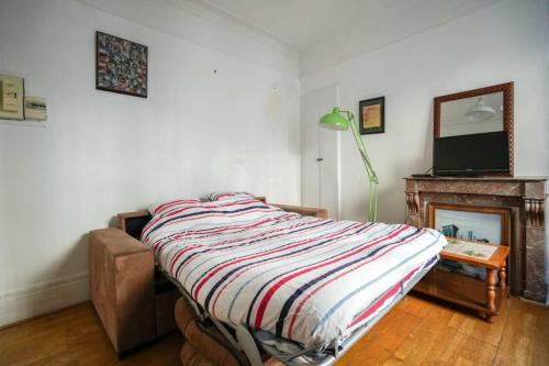 - une chambre avec un lit, une cheminée et une télévision dans l'établissement Lovely studio in Bastille, à Paris