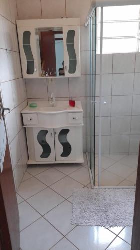 a white bathroom with a sink and a shower at Pousada Recanto dos Pássaros in Imaruí