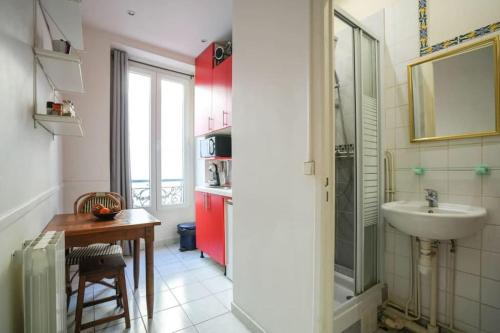 La salle de bains est pourvue d'un lavabo, d'une table et d'un miroir. dans l'établissement Lovely studio in Bastille, à Paris