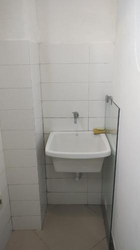 a white sink in a white tiled bathroom at Loft Geribá in Búzios