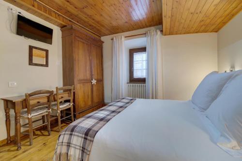 a bedroom with a bed and a table and a desk at Casa Jansú in Escuñau