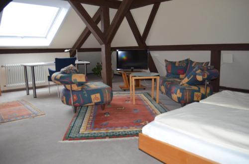 ラウフェンブルクにあるAlte Post - Hotel Am Rhein-Ufer Laufenburgのベッド、椅子、テレビが備わる客室です。