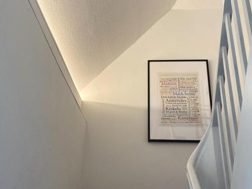 a stairwell with a picture on a white wall at modernes DG Apartment Schloofschdubb Nähe Kassel in Fuldatal