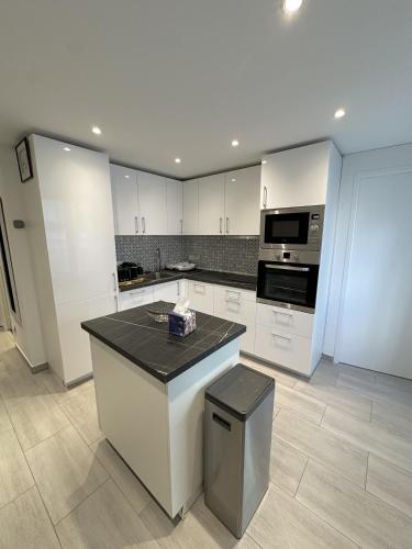 une cuisine avec des armoires blanches et un comptoir noir dans l'établissement Residence Graziella Appartement 100, à Juan-les-Pins