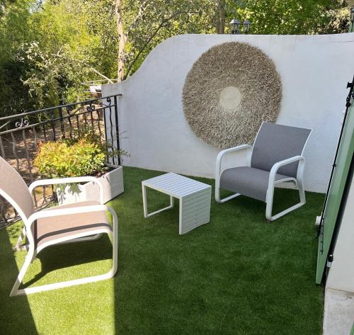a patio with chairs and a table on the grass at Logis Hotel Le Blason de Provence in Monteux