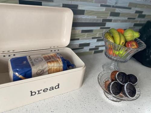 a white lunch box with bread and a bowl of fruit at Fish Eagle Place in Durban
