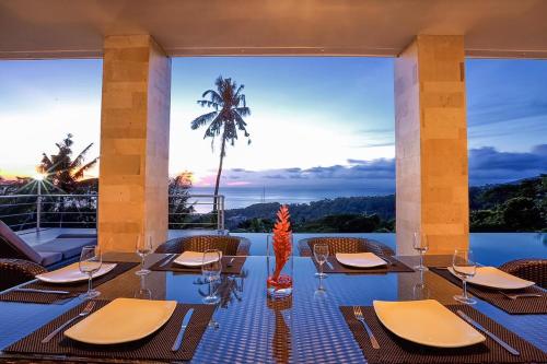 a restaurant with tables and chairs and a palm tree at Villa Skyline Lombok in Lajor