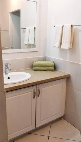 a white bathroom with a sink and a mirror at Secure, Gated Oasis close to City in Port-of-Spain