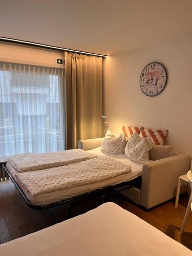 a bedroom with two beds and a couch and a clock at Silver Sunrise Studio in De Haan
