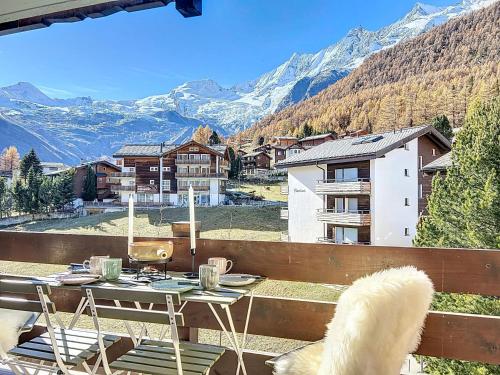 a white dog sitting on a balcony with a table and chairs at Saas-Fee Panorama Studio in Saas-Fee