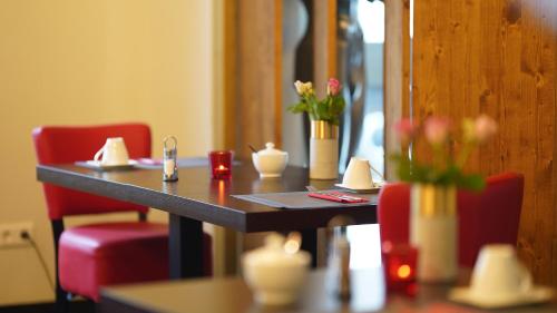 a table with red chairs and a table with flowers at Amical Hotel Hagen - Am Hauptbahnhof in Hagen