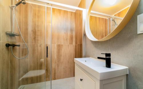 a bathroom with a shower and a sink and a mirror at Apartamenty EverySky Nadrzeczna 3E-3D in Karpacz