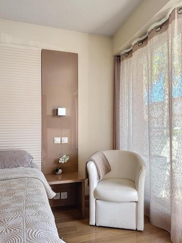 - une chambre avec une chaise, un lit et une fenêtre dans l'établissement Beau studio bord de mer à Villeneuve Loubet French Riviera, à Villeneuve-Loubet