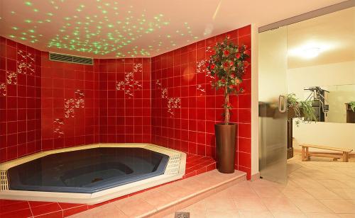 a red tiled bathroom with a tub with a plant at Hotel Dolomites Inn in Canazei